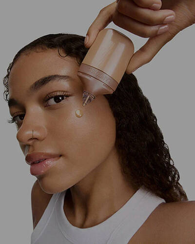 Egy modell egy csepp Lancome folyekony highlightert visz fel az arcara.