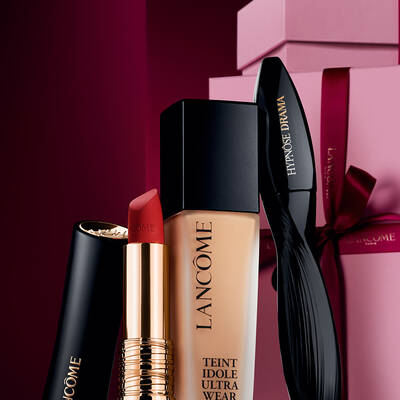 Elegans csendelet Lancome L'Absolu Rouge matt ruzzsal, Teint Idole Ultra Wear alapozoval es Hypnose Drama szempillaspirallal luxus sotetvoros unnepi hatter előtt.