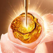 Aranyszinu olajcsepp, amely rozsara csorog, ragyogo fenyekkel es gyenged hatterrel.