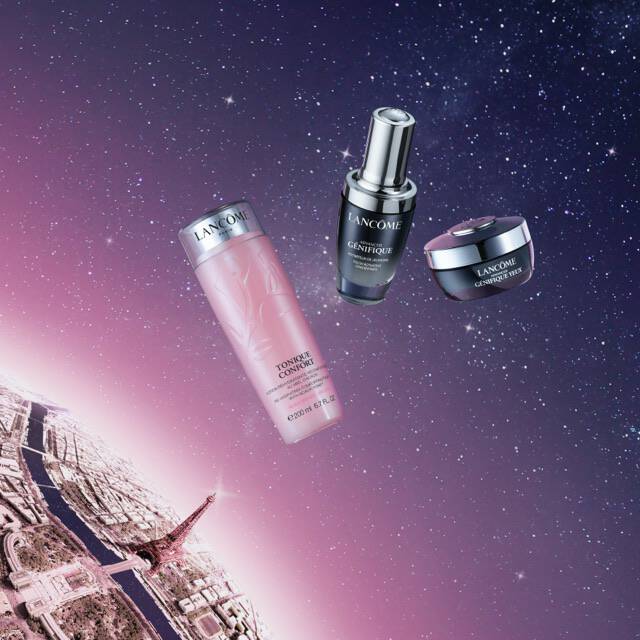 Three skincare products are displayed against a cosmic backdrop featuring stars and a faint view of Paris, including the Eiffel Tower.