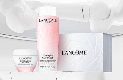 A clean, minimalistic display featuring Lancome skincare products, including a lotion, cream, and box on a light background.