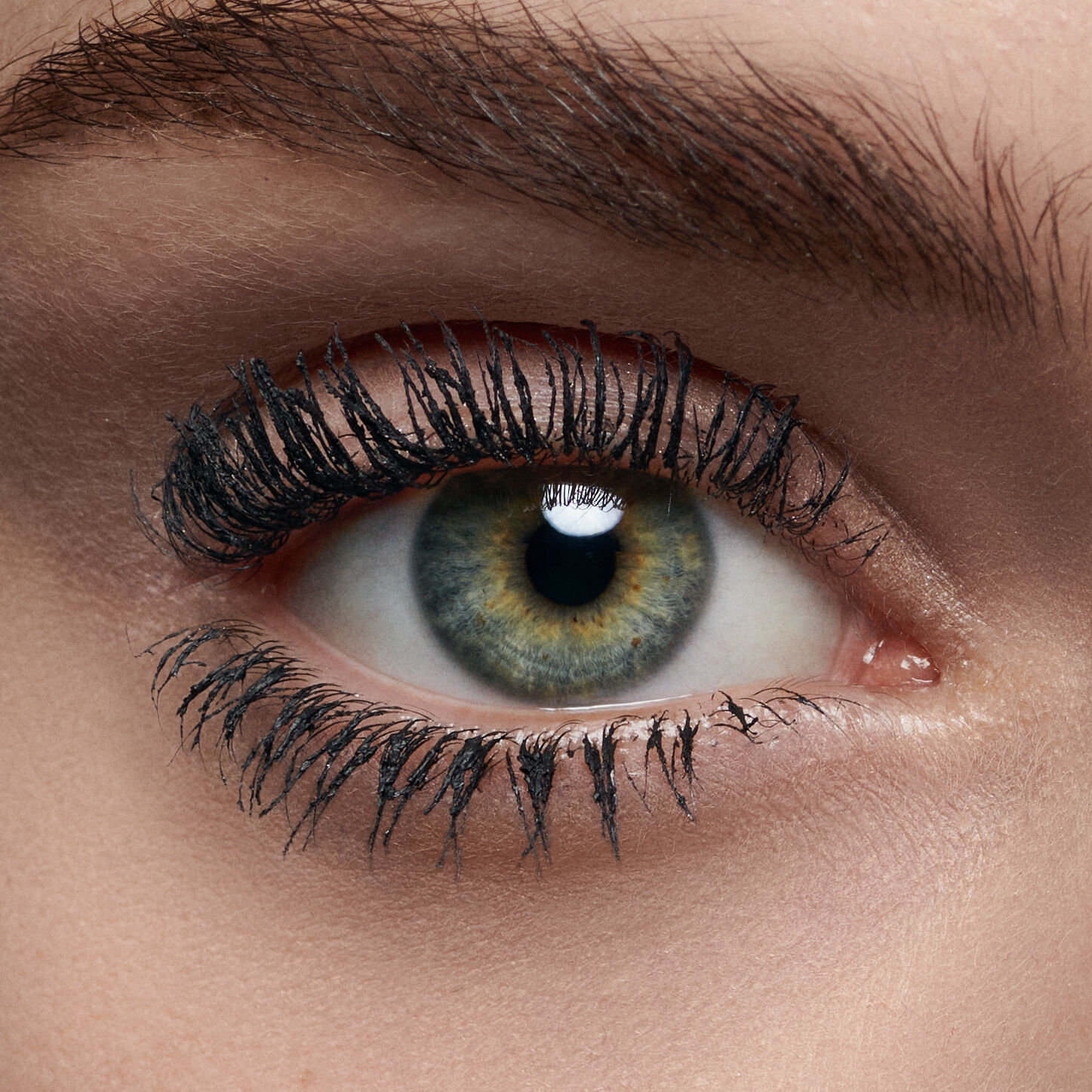 Close-up of a human eye with striking greenish-blue iris, long, dark eyelashes, and a reflective pupil.