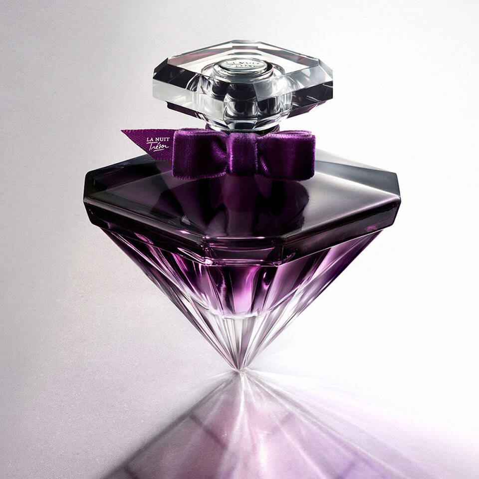 Lila, gyemantformaju parfum uveg, fekete masnival es 'La Nuit Edition' cimkevel, elegans hatter előtt.