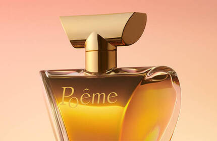 A close-up of a perfume bottle with an elegant design, featuring a gold cap and a clear glass body filled with a warm, amber-colored liquid. The label reads "Poeme." The background has a soft gradient from peach to light pink.