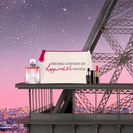 A perfume bottle, a cosmetics bag with the text "THIS BAG CONTAINS MY MAGIC POTION," and makeup products are displayed against a pink and purple gradient sky. In the background, a stylized image of the Eiffel Tower is visible.