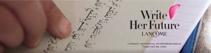 Egy kez egy konyv lapjan ir, a hatterben a „Write Her Future” felirat lathato, a Lancome logojaval.