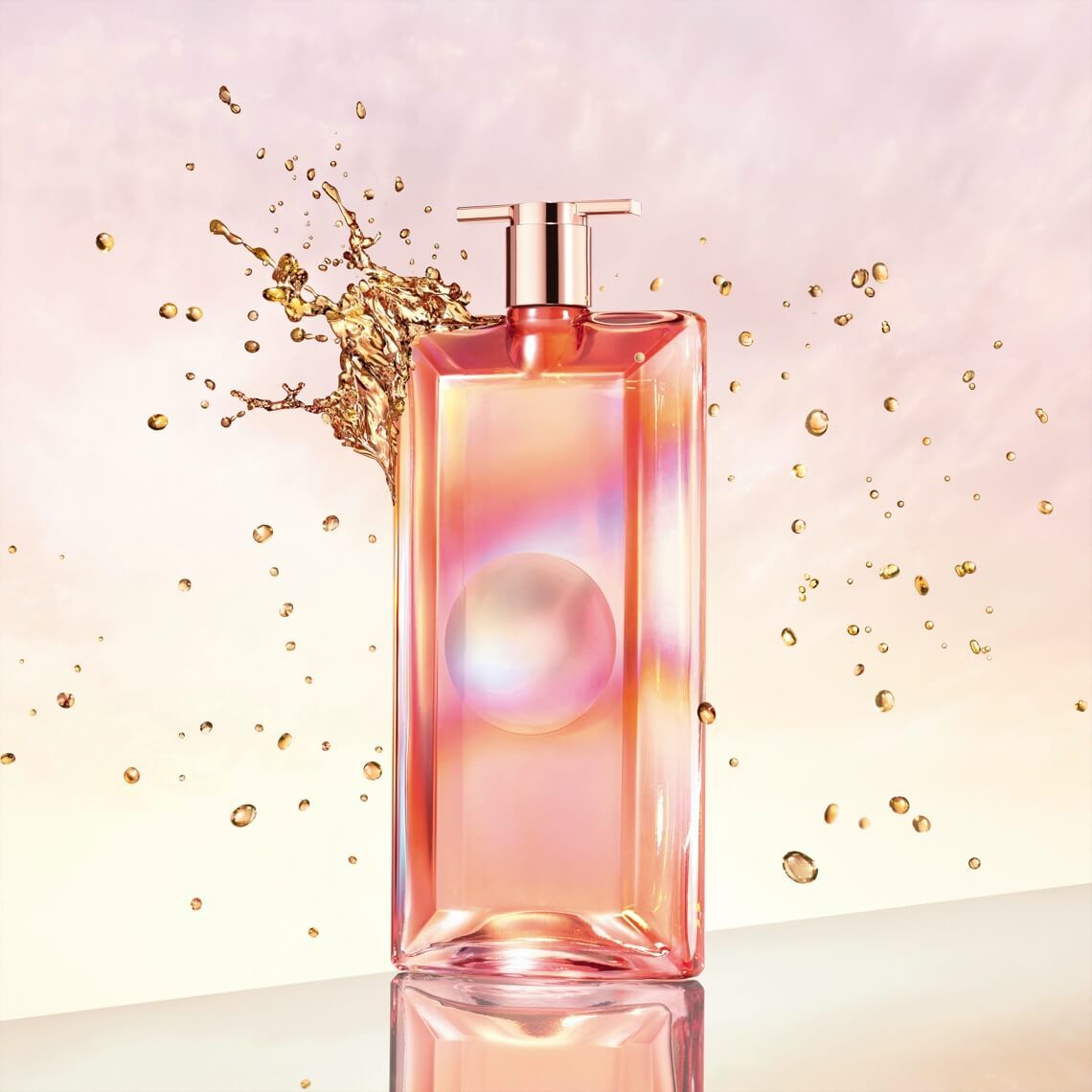 A sleek glass perfume bottle with a pink and gold gradient design, featuring a round logo, surrounded by splashes of golden liquid against a soft pastel background.