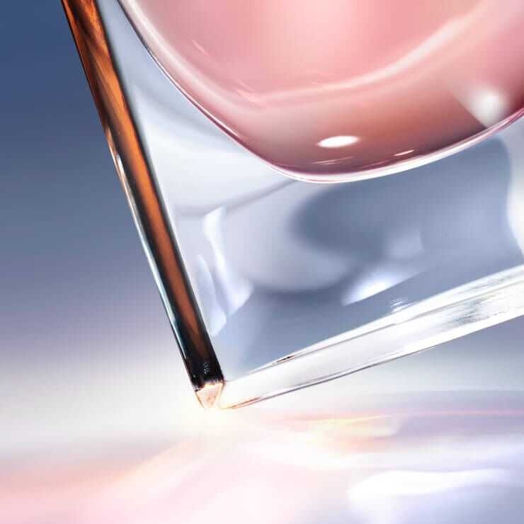 Egy uveg, amelyben rozsaszin folyadek lathato, enyhen dőlten helyezkedik el, visszaverődő fenyekkel a hatterben.