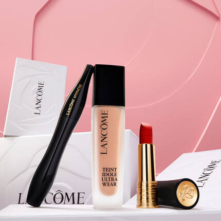 Kez, amely Lancome bőrapolo es sminktermekeket mutat be feher dobozokkal, rozsaszin hatter előtt.