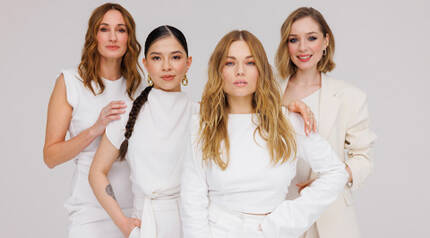 Negy női modell all feher ruhakban, egyesitve stilust es eleganciat a Lancome Squad szamara.