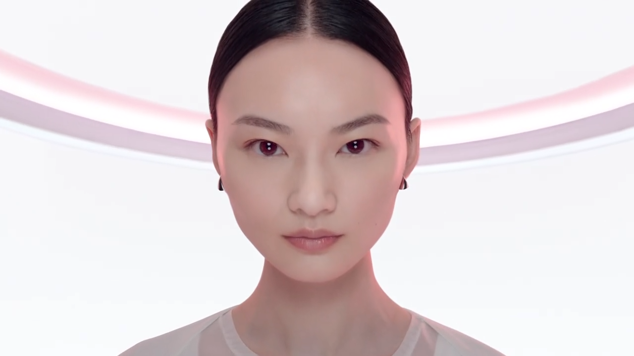 Fiatal nő, sima arccal és fekete hajjal, világos háttér előtt, minimalistikus stílusban.