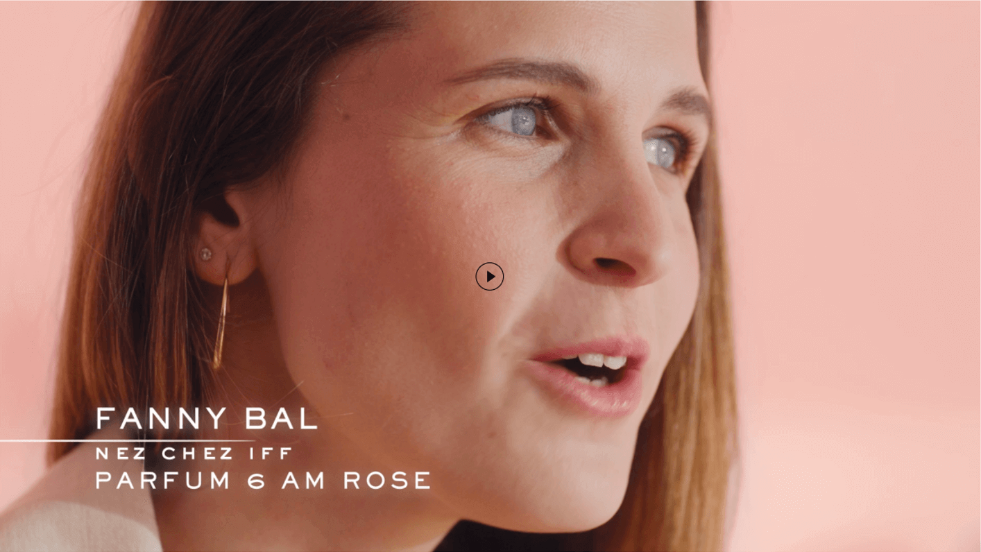 Fiatal nő beszél a Parfum 6 am Rose-ról, rózsaszín háttér előtt, figyelemfelkeltő stílusban.